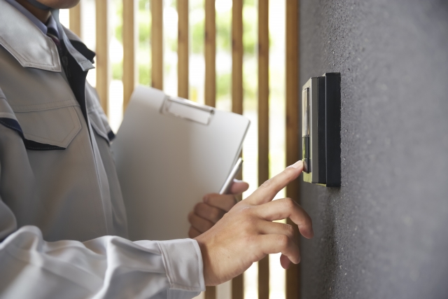 玄関チャイムを押す作業員