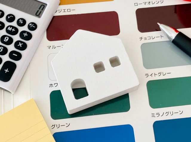 外壁塗装の色見本と住宅模型、電卓とペン
