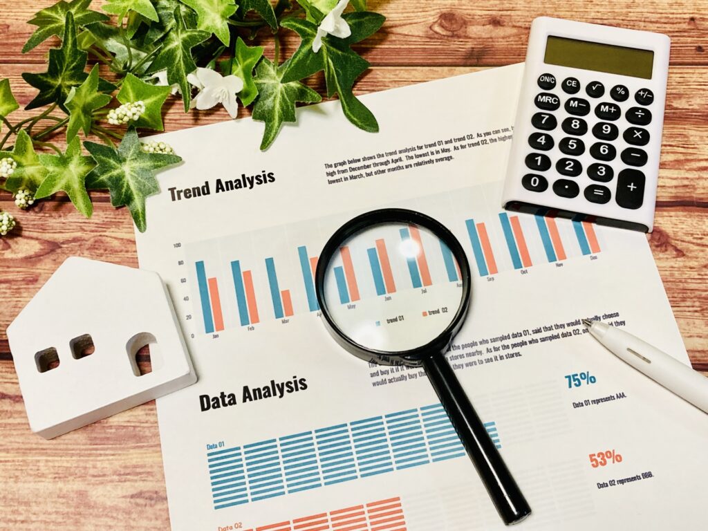 虫眼鏡と電卓と家の模型と資料